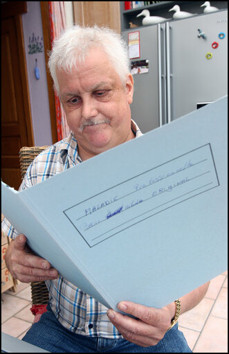 A former carpenter with respiratory cancer who can no longer work shows his health dossier.