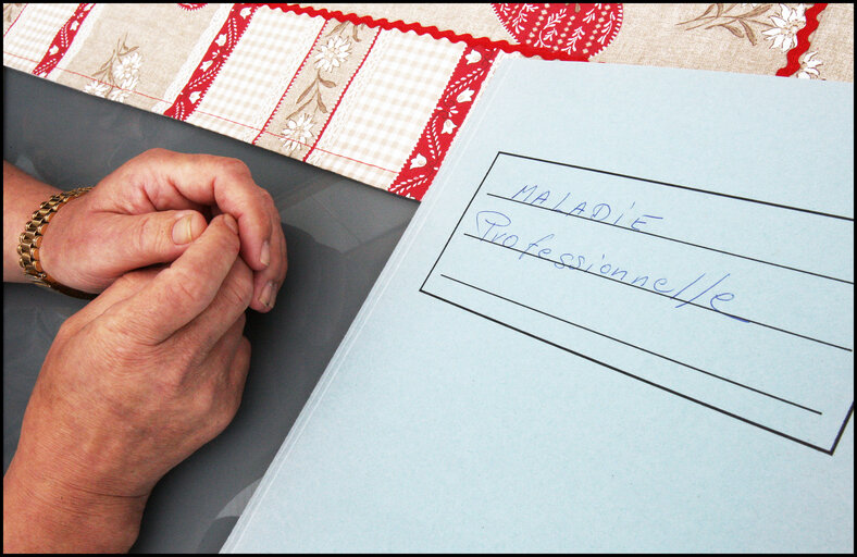 Fotografie 13: A former carpenter with respiratory cancer who can no longer work shows his health dossier.