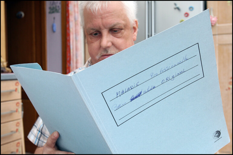 Fotografie 3: A former carpenter with respiratory cancer who can no longer work shows his health dossier.