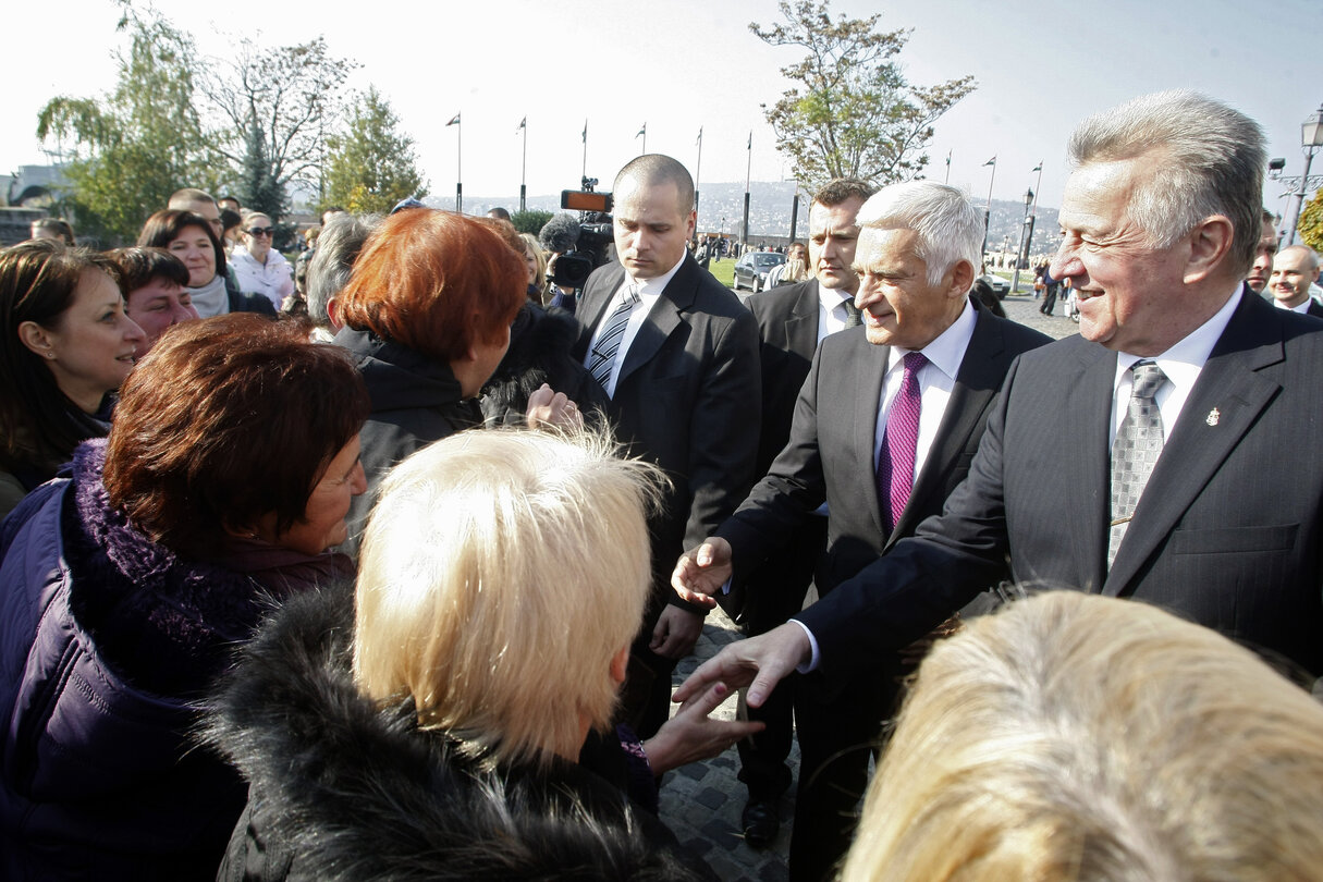 President of the European Parliament Jerzy Buzek (2nd-R) shakes hands with tourists from Poland while Hungarian President Pal Schmitt (R) smiles in front of the 'Sandor' Presidental Palace in the Buda castle in Budapest