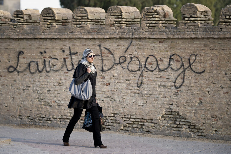 Fotografija 18: Kairouan, Tunisia 20 October 2011  A tunisian woman pass by a graffiti against secularism.  The upcoming Tunisian elections for a Constituent Assembly are scheduled on October 23rd 2011.