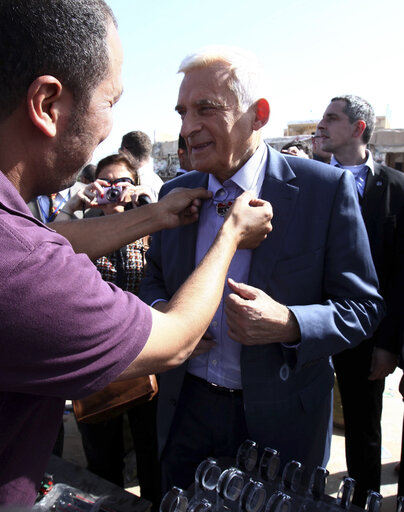 Fotografie 1: A Libyan merchandise seller gives President of the European Parliament Jerzy Buzek a necklace in the shape of the Libyan map during the latter's visit to the Bab Al-Aziziya, former fortified compound of ousted Moamer Kadhafi, in Tripoli on October 30, 2011.