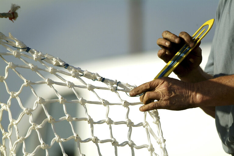 Fotografie 1: Fishermen repairing his net.