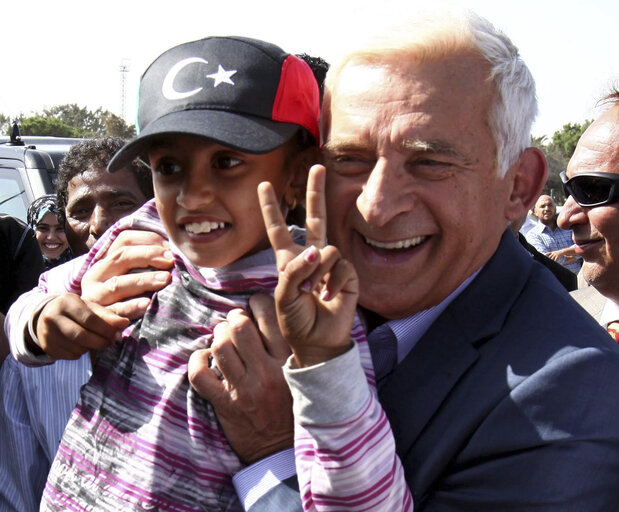 Fotografie 2: President of the European Parliament Jerzy Buzek holds a Libyan child during a visit to the Bab Al-Aziziya, the former fortified compound of ousted Moamer Kadhafi, in Tripoli on October 30, 2011.